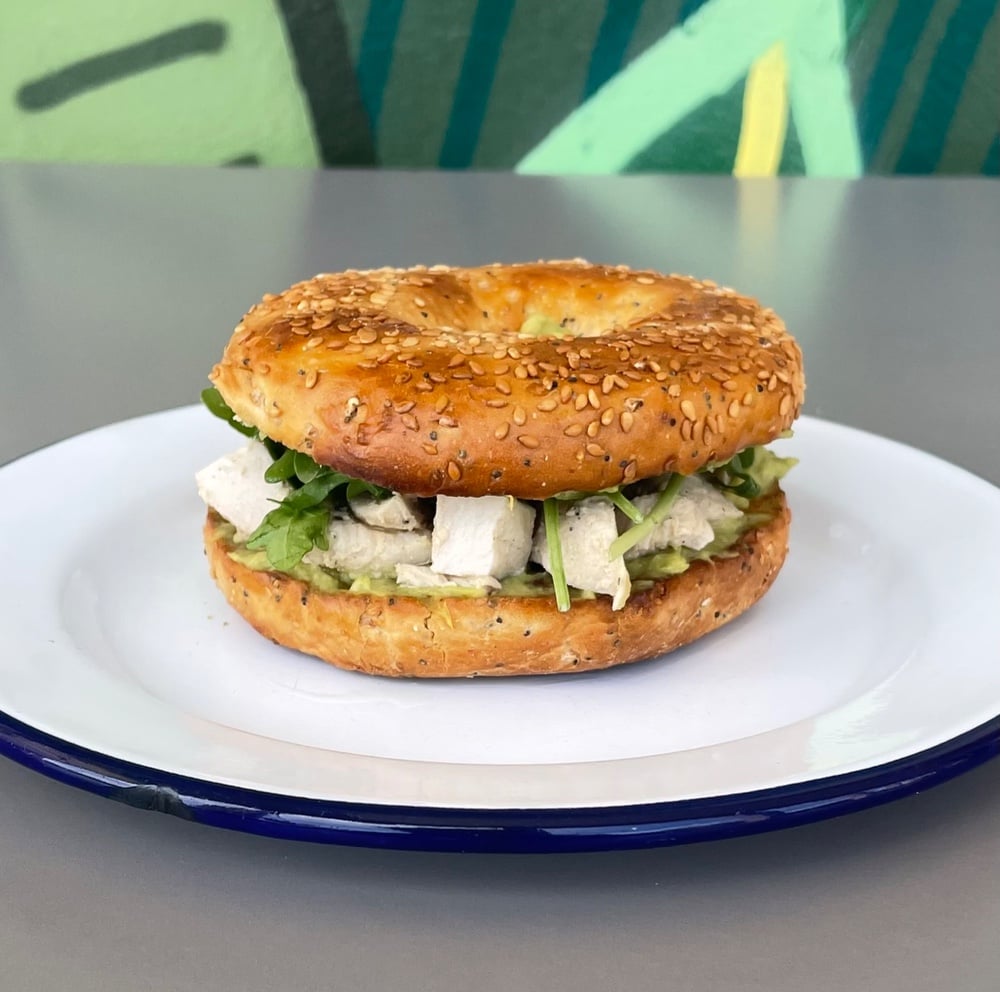 Bagel de aguacate y pollo marinado con rucula y aliño de cacahuete