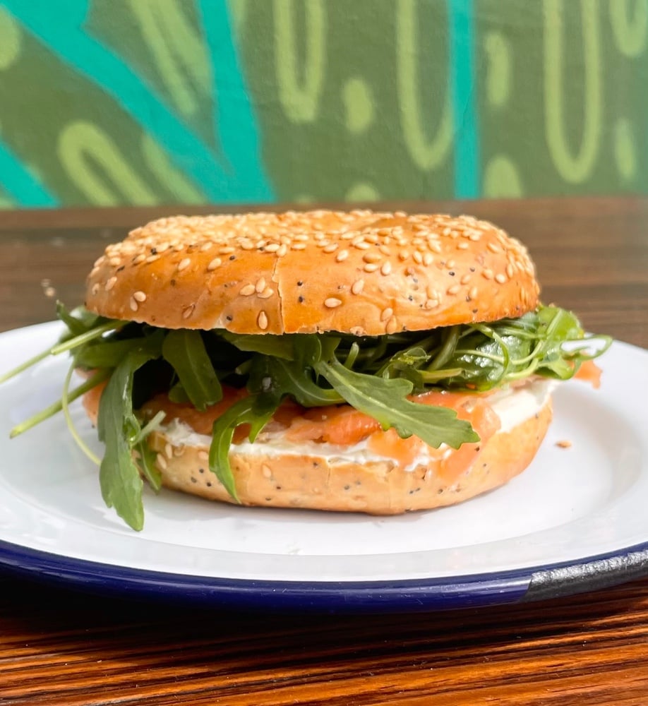 Bagel de salmon con queso suave, mostaza de dijon, limon y rucula.